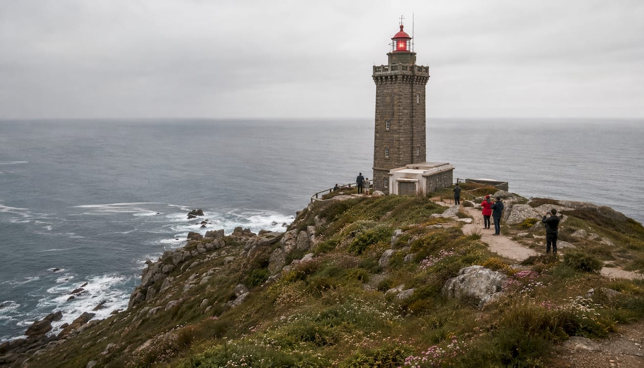 Un visitante contempla el faro atlántico situado sobre un imponente acantilado.
