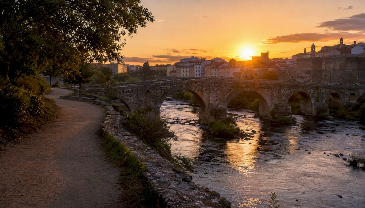 Puente romano sobre el río Miño con un agradable paseo junto a la orilla